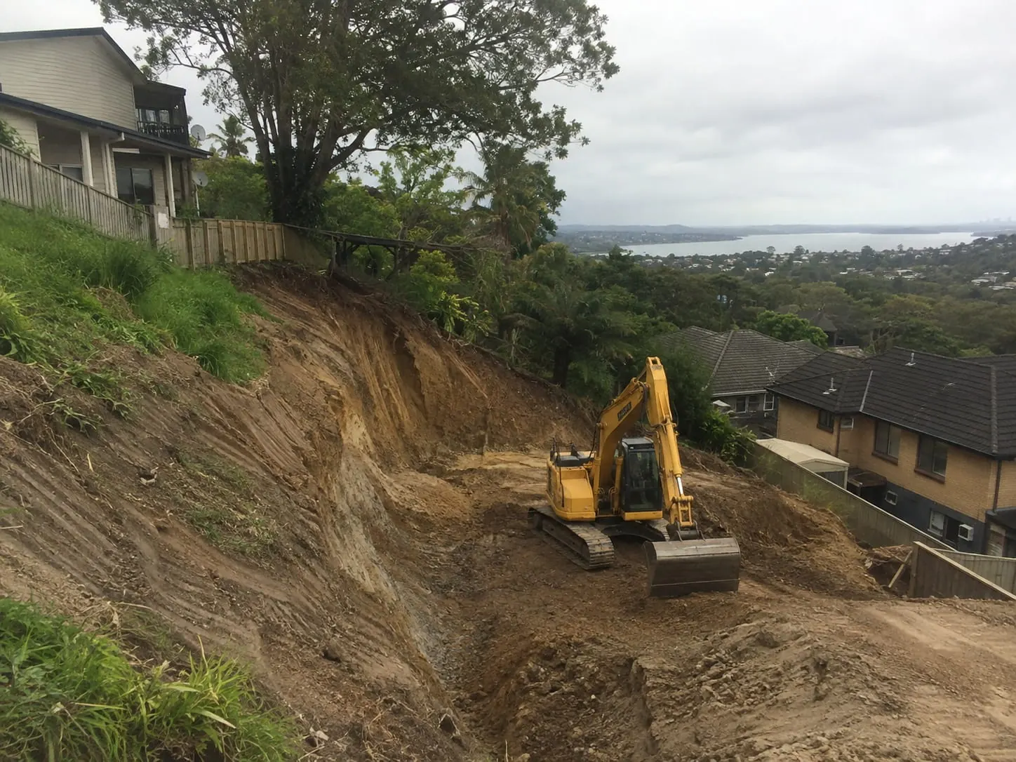 Excavator cutting and levelling a sloped Auckland section